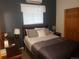 This bedroom features a queen bed, white blinds, and a window A/C unit at 2860 Ames St, Wheat Ridge, CO 80214