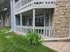 Building exterior with stone accents, a white railing, and green grass at 8600 E Alameda Ave # 105, Denver, CO 80247