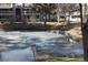 The pond is partially frozen and surrounded by mature trees near a residential building at 8600 E Alameda Ave # 105, Denver, CO 80247