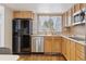 Kitchen view with wood cabinets, stainless steel dishwasher, sink and a black refrigerator at 7176 S Vine E Cir, Centennial, CO 80122