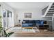 Bright living room with hardwood floors, a modern blue sectional couch, and a large picture window at 7176 S Vine E Cir, Centennial, CO 80122