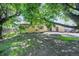 Fenced backyard with grassy areas, brick home, mature trees and concrete patio at 892 S Union Blvd, Lakewood, CO 80228