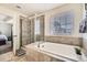 Bathroom featuring a soaking tub, a glass-enclosed shower, and a window that provides ample natural light at 13341 Olive St, Thornton, CO 80602