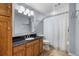 Bathroom with dark countertop, wood cabinets, large mirror, and shower with white curtain at 3063 E 148Th Pl, Thornton, CO 80602