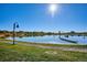 Picturesque lake view featuring a walking path, a boat, and lush green grass under a bright, sunny sky at 5128 W 26Th Ave # 208, Denver, CO 80212