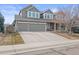 Gray two-story house featuring stone accents, three-car garage, and expansive driveway at 8775 Wild Horse Way, Frederick, CO 80504