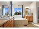 Bright bathroom with dual sinks, large tub, blue accents, and large vanity mirror at 8775 Wild Horse Way, Frederick, CO 80504