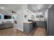 Updated kitchen features sleek gray cabinets, stainless steel appliances, and wooden flooring with an open access to the living room at 16120 E Radcliff Pl, Aurora, CO 80015