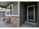 Inviting front porch with gray siding, stone accents, and a dark blue front door with decorative wreath at 26554 E Indore Ave, Aurora, CO 80016