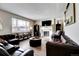 Cozy living room with a fireplace, dark leather couches, and large windows providing ample natural light at 26554 E Indore Ave, Aurora, CO 80016
