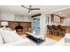 Open concept living room connected to the kitchen with a fireplace and ceiling fan at 3807 S Jasmine St, Denver, CO 80237