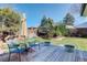Secluded backyard featuring a wooden deck with patio seating, mature trees, and green grass at 6071 S Ingalls St, Littleton, CO 80123