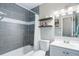 Well-lit bathroom featuring a shower over tub with gray tile surround and floating wooden shelves at 6071 S Ingalls St, Littleton, CO 80123