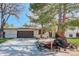 Inviting home exterior features a two-car garage, a well-manicured lawn, and mature trees at 6071 S Ingalls St, Littleton, CO 80123