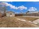 Large backyard featuring a detached garage, wooden fence, and ample green space under a blue, cloudy sky at 3280 Ames St, Wheat Ridge, CO 80212