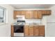 Functional kitchen with oak cabinets, white appliances, and laminate countertops at 3280 Ames St, Wheat Ridge, CO 80212