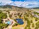 An aerial view of the community featuring a pond, roads, mountains in the distance, and beautiful foliage at 23585 Genesee Village Rd # E, Golden, CO 80401