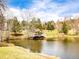 Scenic view of a pond with a wooden dock surrounded by green lawns and trees at 23585 Genesee Village Rd # E, Golden, CO 80401