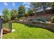 Lush backyard featuring a large grassy area, retaining wall with foliage, and mature trees for shade at 3102 Fox Sedge Pl, Highlands Ranch, CO 80126