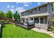 Well-maintained backyard with manicured lawn, a deck with outdoor seating and a grey two-story home at 3102 Fox Sedge Pl, Highlands Ranch, CO 80126