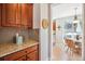 Butler's pantry featuring granite counters, wood cabinets and bar seating with views to kitchen eating area at 3102 Fox Sedge Pl, Highlands Ranch, CO 80126