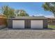A two-car detached garage with white doors, gray wood, gravel base, and backyard area at 5555 Julian St, Denver, CO 80221