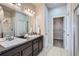 Bathroom featuring double sinks, dark cabinets, a large mirror, and a walk-in shower at 11926 Barrentine Loop, Parker, CO 80138