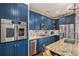 Beautiful kitchen featuring blue cabinetry, stainless steel appliances, and a granite-topped island with sink at 4318 Fossil Way, Castle Rock, CO 80109