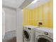 Bright laundry room featuring a newer washer and dryer with yellow striped accent wall and storage at 8437 Thunder Ridge Way # 202, Highlands Ranch, CO 80126