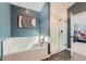 Modern bathroom featuring a soaking tub, glass-enclosed shower, and stylish gray and white tiling at 15290 W 69Th Pl, Arvada, CO 80007