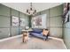 Comfortable home office with olive green walls, a blue loveseat, and custom shelving at 15290 W 69Th Pl, Arvada, CO 80007