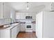 A well-lit kitchen features sleek white cabinets, stainless steel appliances, and beautiful hardwood floors at 10895 W Bowles Pl, Littleton, CO 80127