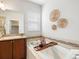 Relaxing bathroom featuring a soaking tub with tiled accents and decorative wall hangings at 1344 S Coolidge Cir, Aurora, CO 80018