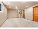 Finished basement room with carpet and painted walls, leading to the stairs and a wooden door at 11530 Elm Ct, Thornton, CO 80233