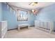 Bedroom with a crib and bench. Blue walls with balloons and a rainbow add a whimsical feel at 11530 Elm Ct, Thornton, CO 80233