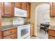 Traditional kitchen featuring wood cabinetry, white appliances, and an adjacent dining area at 11530 Elm Ct, Thornton, CO 80233