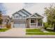 Charming two-story home featuring a covered porch, gray siding and a two car attached garage and landscaped front yard at 15389 E 99Th Way, Commerce City, CO 80022