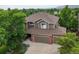 Exterior aerial view of two-story home with three car garage, mature trees, and landscaping at 15962 W 70Th Dr, Arvada, CO 80007