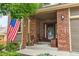Inviting front porch with brick facade, seating, and an American flag displayed at 15962 W 70Th Dr, Arvada, CO 80007