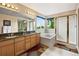 Bright bathroom with a double sink vanity, a bathtub, and a glass shower at 15962 W 70Th Dr, Arvada, CO 80007