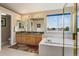Bright bathroom with a double sink vanity, a bathtub, and a glass shower at 15962 W 70Th Dr, Arvada, CO 80007