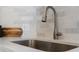 Close-up of the kitchen sink featuring a brushed nickel faucet and tiled backsplash at 11195 Alcott St # D, Westminster, CO 80234