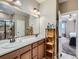 Well-lit bathroom with double sinks, wooden cabinets, and a tiled shower in the background at 7845 S Flat Rock Way, Aurora, CO 80016
