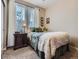 Comfortable bedroom featuring a bed with decorative pillows and a side table under large window at 7845 S Flat Rock Way, Aurora, CO 80016