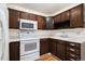 Efficient kitchen with white appliances, dark wood cabinets, and a corner sink at 350 S Clinton St # 2A, Denver, CO 80247