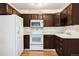 Functional kitchen with white appliances, dark wood cabinets, and plenty of counter space at 350 S Clinton St # 2A, Denver, CO 80247