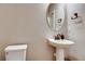 Compact powder room with a pedestal sink, oval mirror, and a neutral color scheme for a clean look at 1839 Morgan Dr, Erie, CO 80516