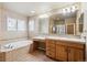Bright bathroom features double windows over a soaking tub and a vanity with a large mirror at 9362 S Holland Way, Littleton, CO 80127