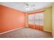 Bright bedroom with orange accent wall, carpet, and sunny windows with sheer curtains at 9362 S Holland Way, Littleton, CO 80127