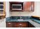Close-up of wet bar features marble countertop, sink, and wood cabinets at 9362 S Holland Way, Littleton, CO 80127